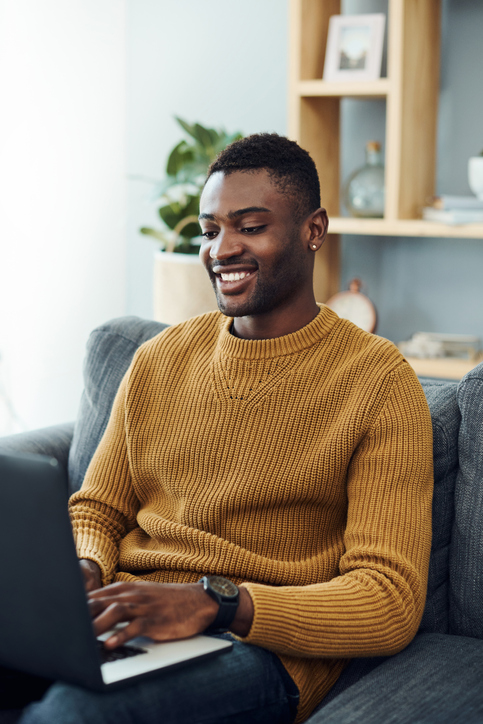 Young man conversing remotely with someone on his laptop at home.