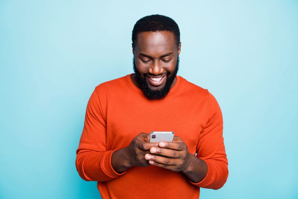 Man smiling while typing on his phone.